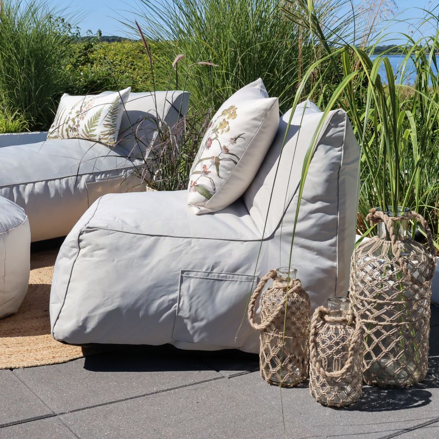 Lazyday outdoor seating in soft grey, styled with botanical cushions among tall grasses and woven lanterns.