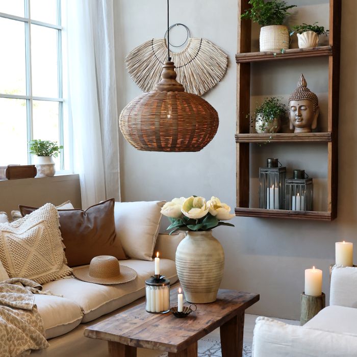 Warm, neutral living room with woven pendant light, rustic wooden furniture, textured cushions, candles and natural decorative accents.